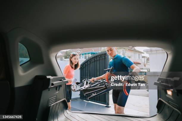 asian chinese couple loading road bike into car trunk at front yard garage getting ready for road trip adventure during weekend morning - asian couple garage car stock pictures, royalty-free photos & images