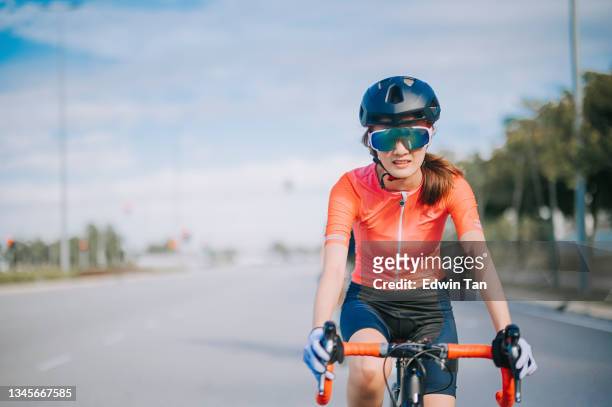 asian chinese young female cyclist riding road bike during weekend morning in city street - forward athlete stockfoto's en -beelden