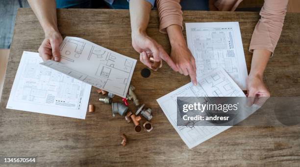 couple trying to fix some pipes in the kitchen at home - instruction manual stockfoto's en -beelden