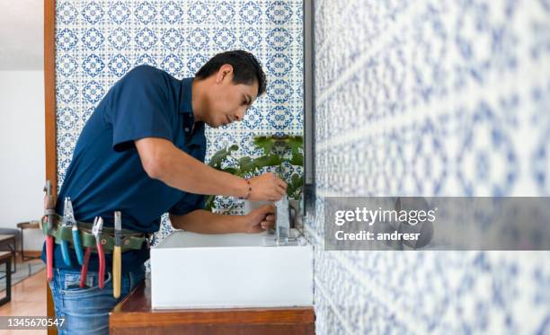 plumber installing a faucet in a bathroom's sink - plumber stockfoto's en -beelden