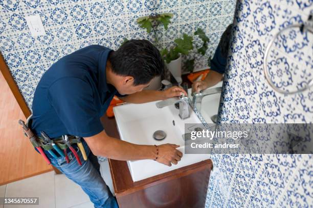 plumber installing a faucet in a bathroom's sink - laying stock pictures, royalty-free photos & images