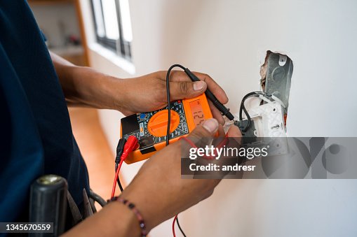 Electrician fixing an electrical outlet and measuring the voltage Electrician fixing an electrical outlet and measuring the voltage