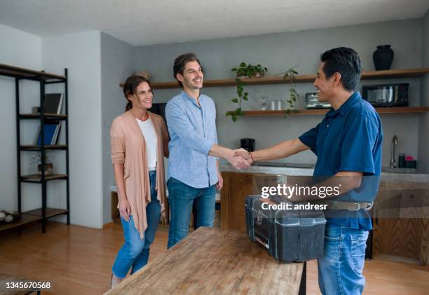 plumber greeting happy clients at home with a handshake - canalizador imagens e fotografias de stock