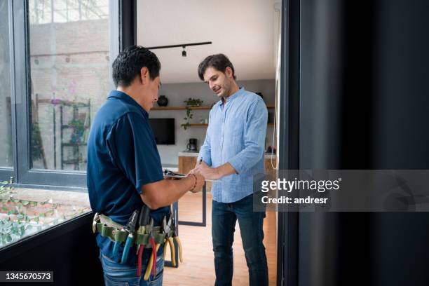 man opening the door of his house to an electrician and signing a report - electrician 個照片及圖片檔