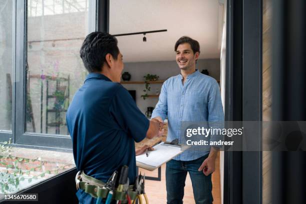 electricista saludando a un cliente con un apretón de manos en la puerta de su casa - arreglar fotografías e imágenes de stock