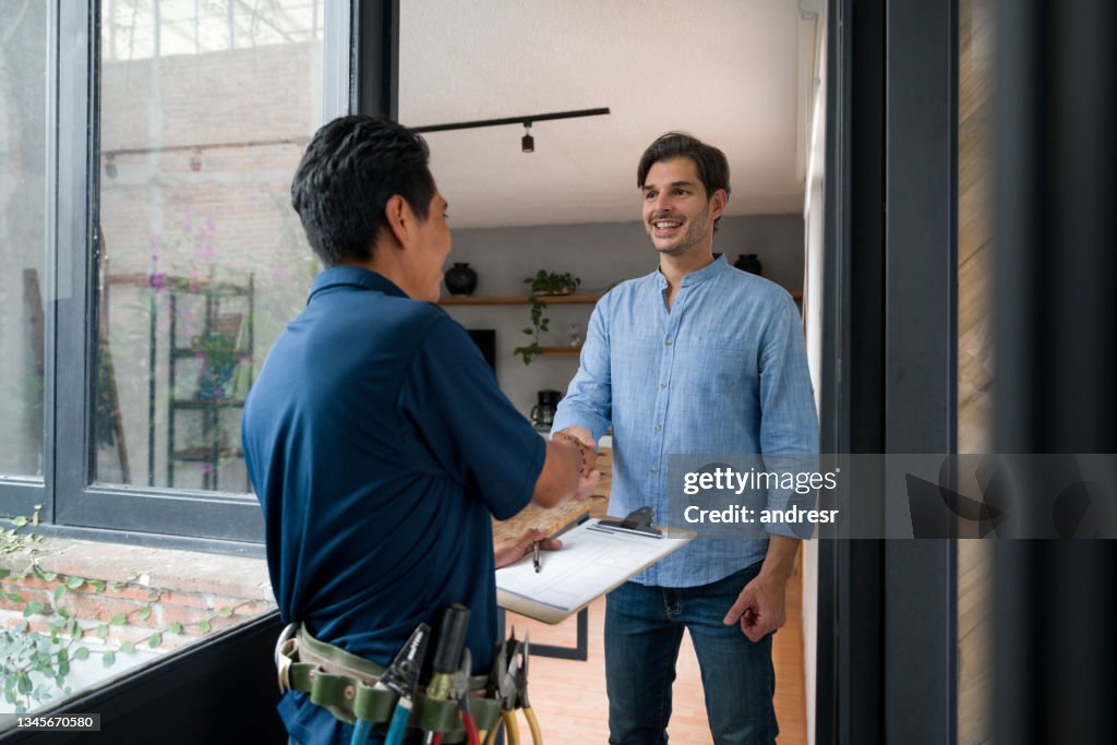 Electrician greeting a client with a handshake at the door of his house