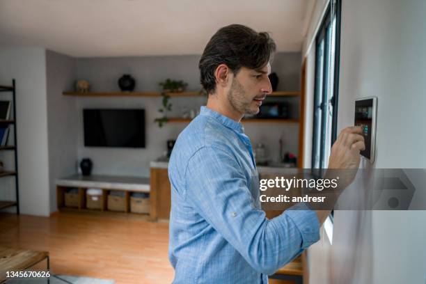 man leaving his house and locking the door with an automated security system - burglar alarm stock pictures, royalty-free photos & images