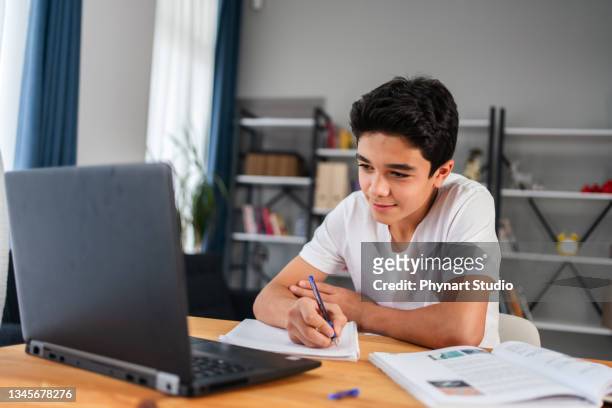 teenage boy with laptop having online school class at home - arab on computer imagens e fotografias de stock