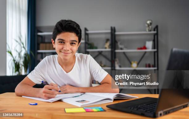 adolescent avec ordinateur portable ayant un cours d’école en ligne à la maison - élève 12 ans photos et images de collection