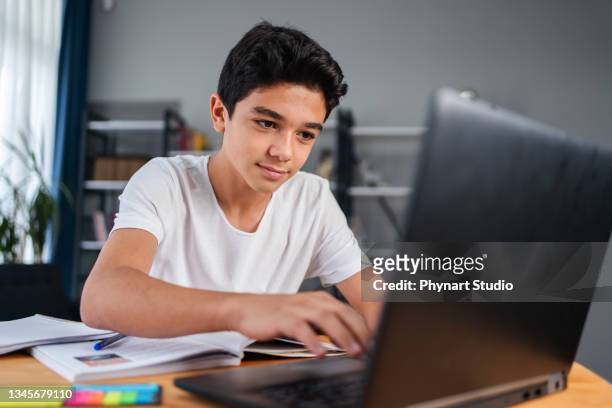 adolescent avec ordinateur portable ayant un cours d’école en ligne à la maison - élève 12 ans photos et images de collection