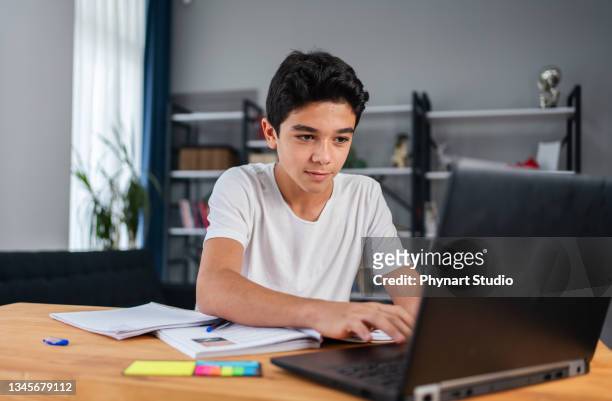 adolescent avec ordinateur portable ayant un cours d’école en ligne à la maison - arab student kids photos et images de collection