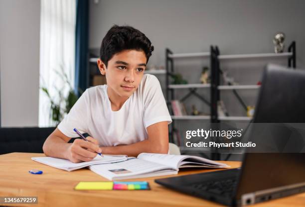 teenage boy with laptop having online school class at home - learn arabic stock pictures, royalty-free photos & images