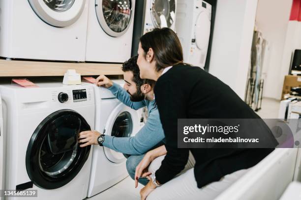 beautiful and happy young couple buying in modern appliances store. - buying washing machine stockfoto's en -beelden