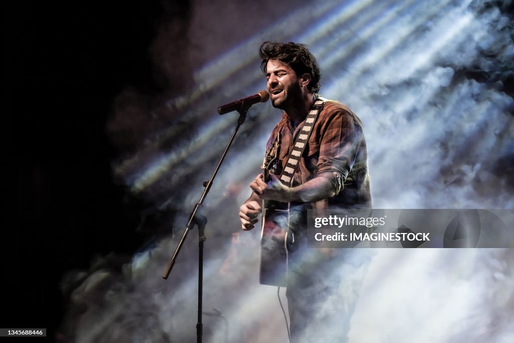 Man singing and playing the guitar in front of the microphone