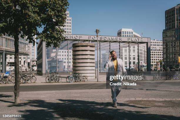 businessman talking on mobile phone in city - potsdamer platz stock pictures, royalty-free photos & images