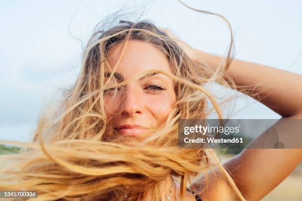 beautiful young woman with hand in hair - tossing hair facing camera woman outdoors stock-fotos und bilder