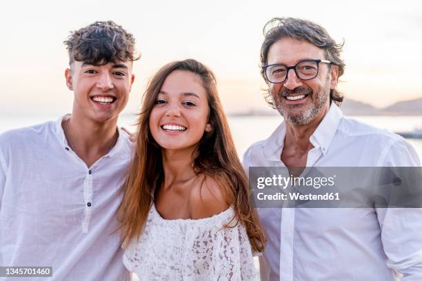 beautiful woman standing with father and brother at beach - southern european descent stock pictures, royalty-free photos & images