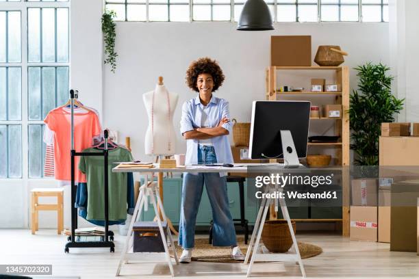 confident female fashion designer with arms crossed standing at studio - stilista di moda foto e immagini stock