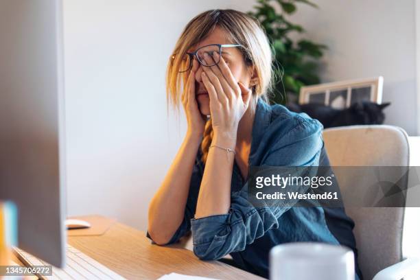 tired female influencer rubbing eyes at table - rubbing eyes stock pictures, royalty-free photos & images