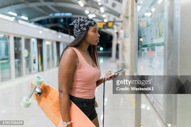woman with skateboard and mobile phone checking map at station - looking at subway map bildbanksfoton och bilder