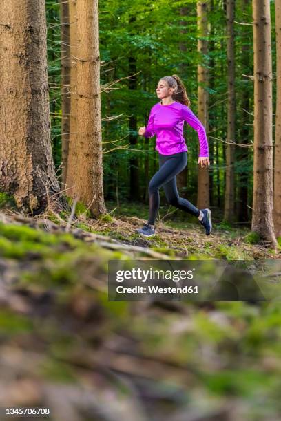 female athlete running in forest - jogster stockfoto's en -beelden