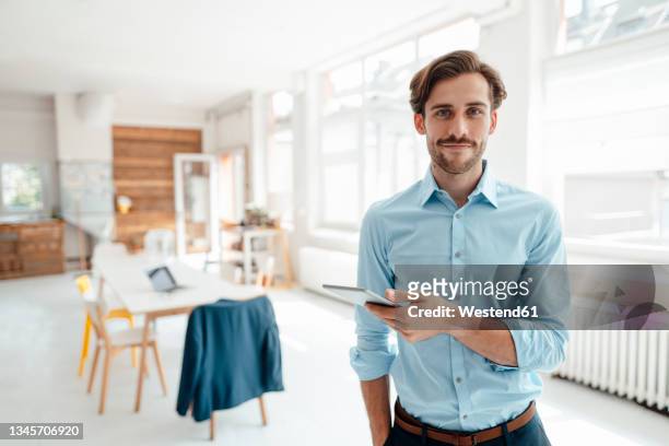 male business professional with digital tablet at office - solo un uomo giovane foto e immagini stock