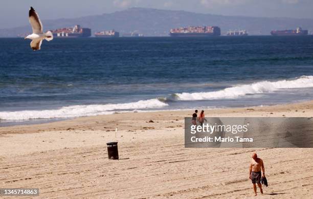 People walk on a mostly empty Huntington Beach about one week after an oil spill from an offshore oil platform on October 9, 2021 in Huntington...
