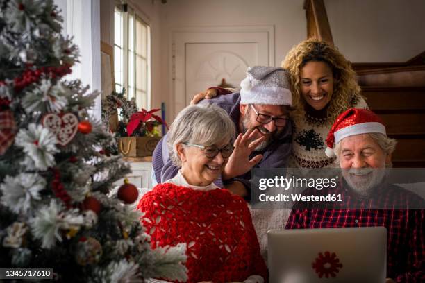 man waving hand while attending video call with family during christmas - old man woman christmas stock pictures, royalty-free photos & images