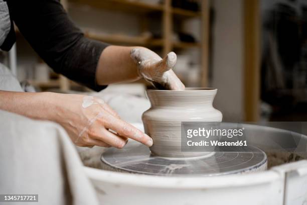 young craftswoman making flower pot on pottery wheel - aardewerk stockfoto's en -beelden