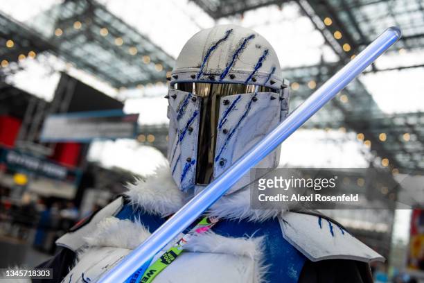 Ryan Kelly, from New Jersey, dressed as Star Wars' The Mandalorian poses with a lightsaber at Day 3 of New York Comic Con at Javits Center on October...