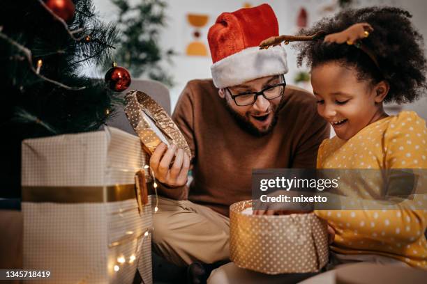 feliz padre e hija abriendo juntos los regalos de navidad - desenvolver fotografías e imágenes de stock
