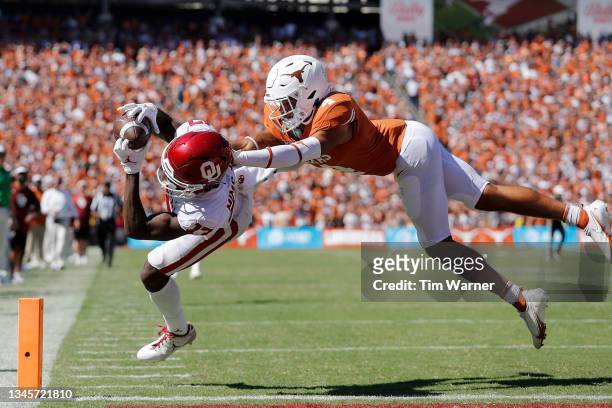Marvin Mims of the Oklahoma Sooners catches a pass for a touchdown while defended by Darion Dunn of the Texas Longhorns in the fourth quarter during...