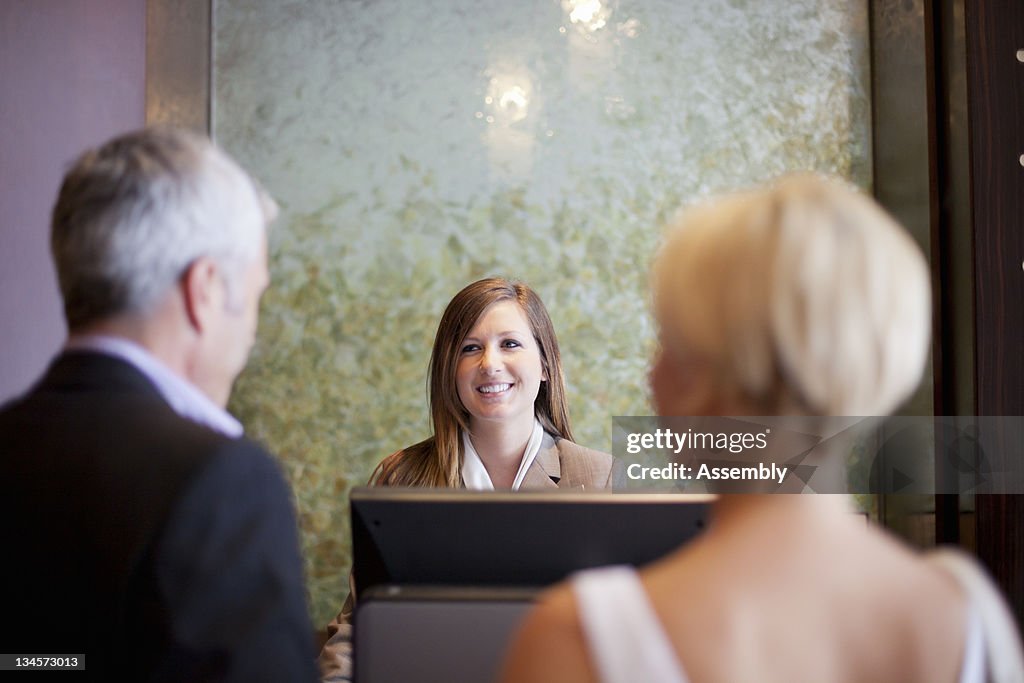A couple at a hotel front desk.