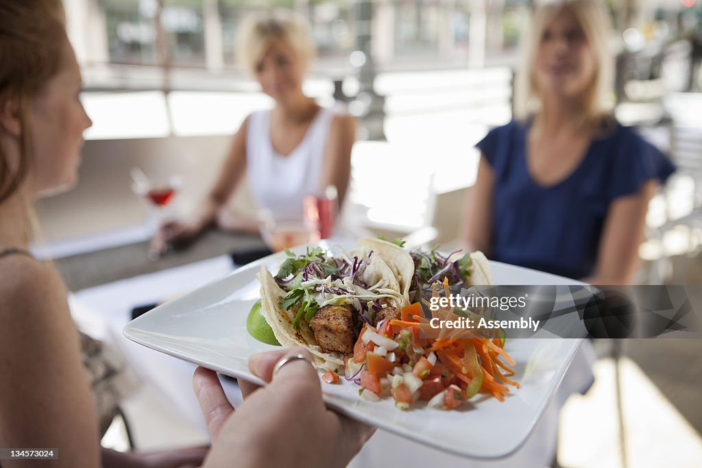 Server bringing patrons taco plate at restaurant.