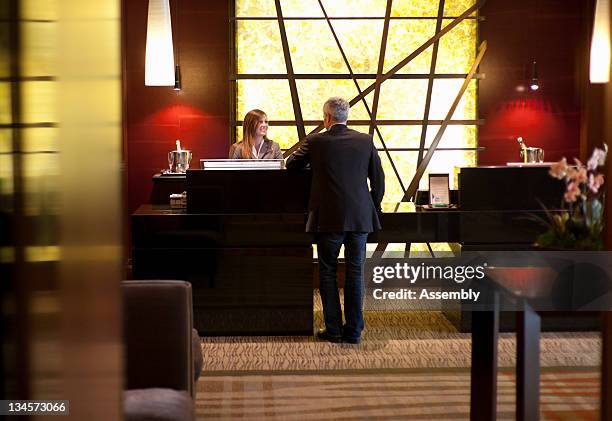 mature man at reception desk in hotel lobby. - reception stock-fotos und bilder