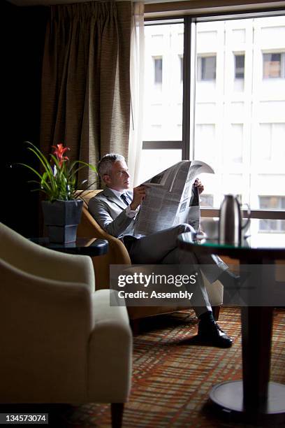 mature businessman reading newspaper in lounge - newspaper luxury bildbanksfoton och bilder