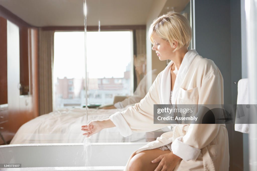 Woman in a hotel draws herself a bath.