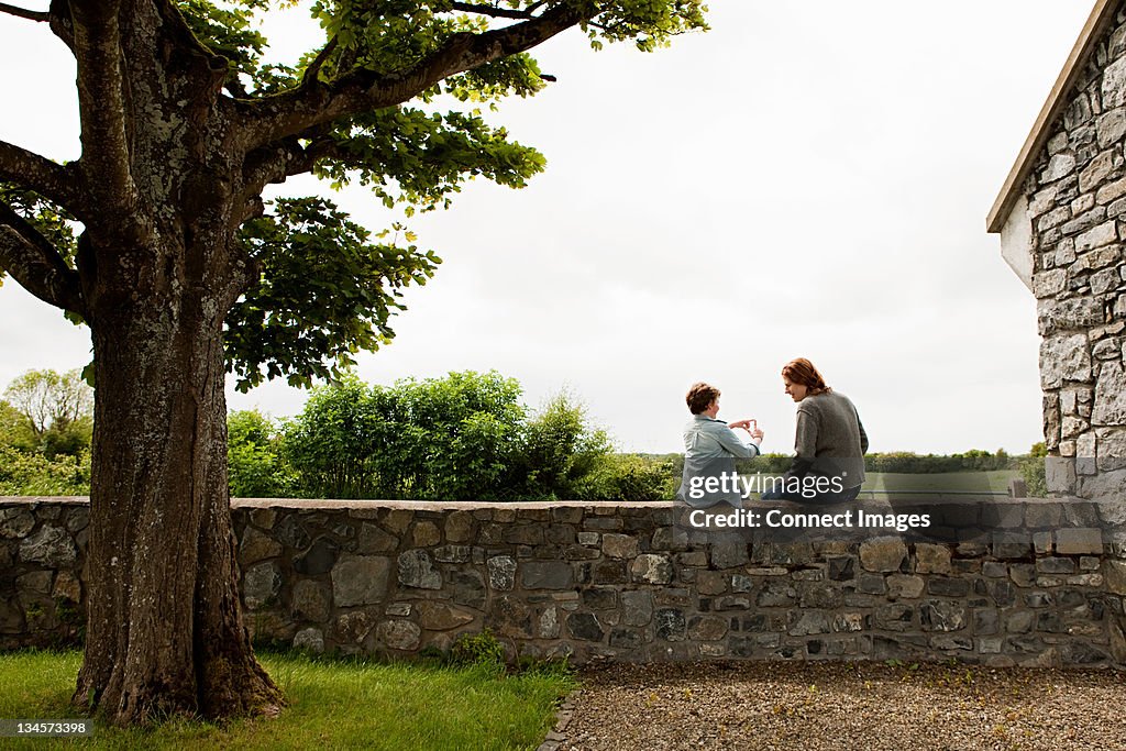 Father and son sitting on stone wall