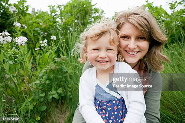 mutter und tochter sitzen im feld, blick in die kamera - irish family stock-fotos und bilder