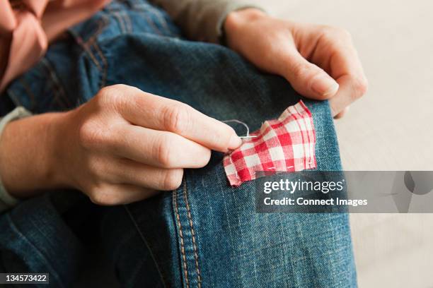 woman repairing jeans, close up - textile patch stock pictures, royalty-free photos & images