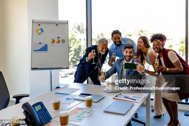 multi-ethnic group of coworkers are celebrating a birthday party in the office and taking a self portrait. - global gift stock pictures, royalty-free photos & images