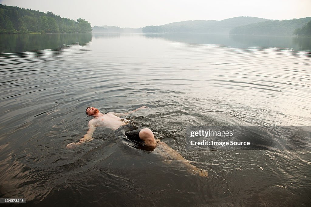 Mid adult man swimming in lake