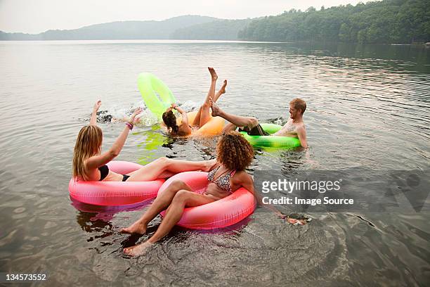 Friends playing in inflatable rings on lake