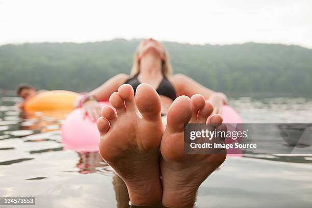 close up of young woman floating in lake - low section stockfoto's en -beelden