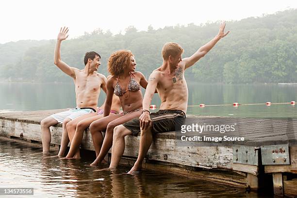 friends turning to wave from pier on lake - friends waving stock pictures, royalty-free photos & images