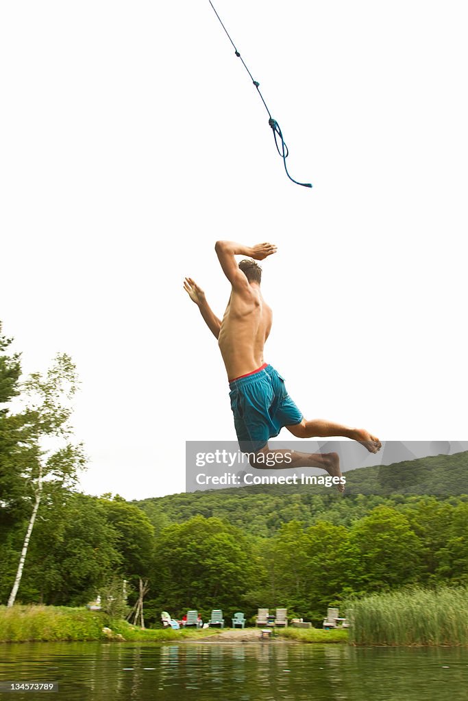 Teenage boy balanceo de una cuerda en un lago