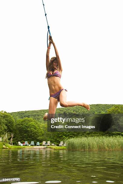 teenager-mädchen schaukeln auf einem seil in einem see - den sprung wagen stock-fotos und bilder