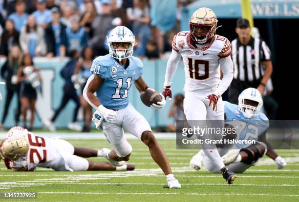 Josh Downs of the North Carolina Tar Heels makes a catch as Jammie Robinson of the Florida State Seminoles gives chase during the second half of...