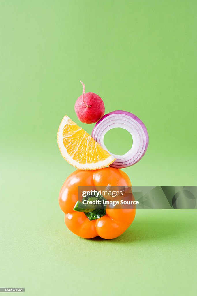 Arrangement of pepper, onion, orange and radish against green background