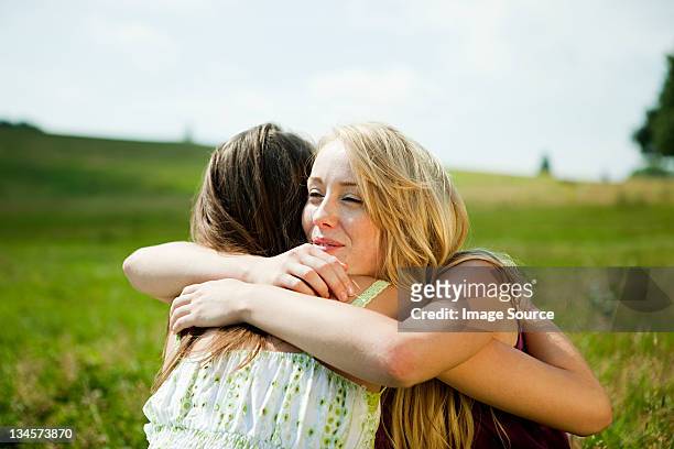 young women embracing in a field - sorry stock pictures, royalty-free photos & images